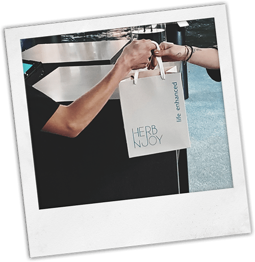 employee handing customer an HerbNJoy shopping bag